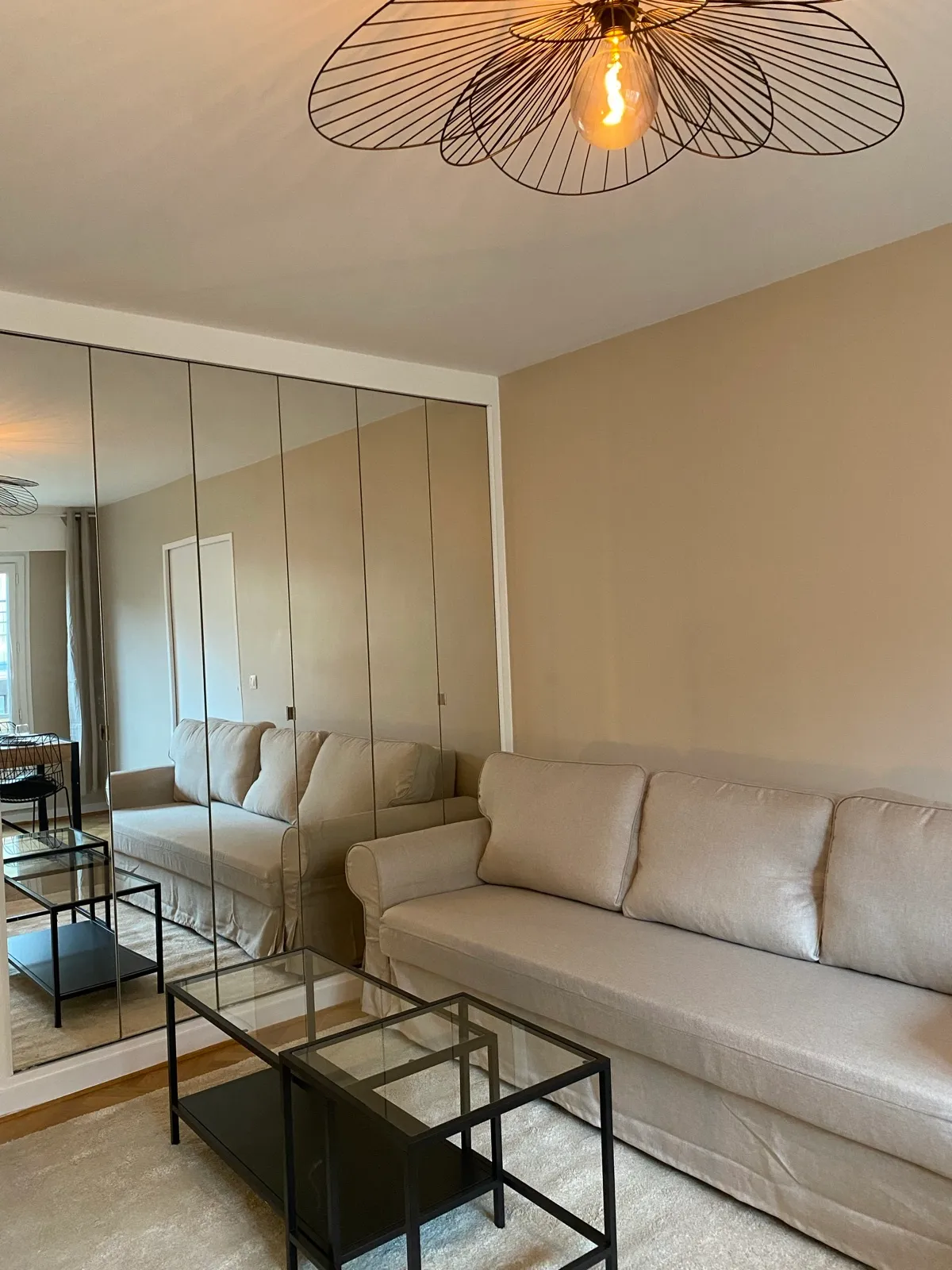 Salon avec canapé confortable et mur de miroirs